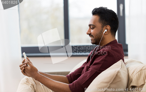 Image of man in earphones listening to music on smartphone