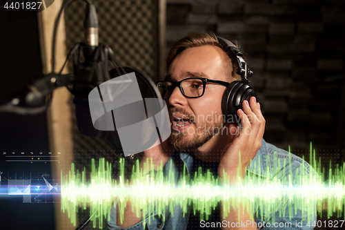 Image of man with headphones singing at recording studio