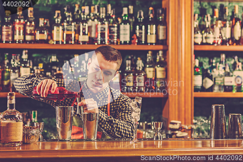 Image of Barman making an alcoholic cocktail at the bar counter on the bar background