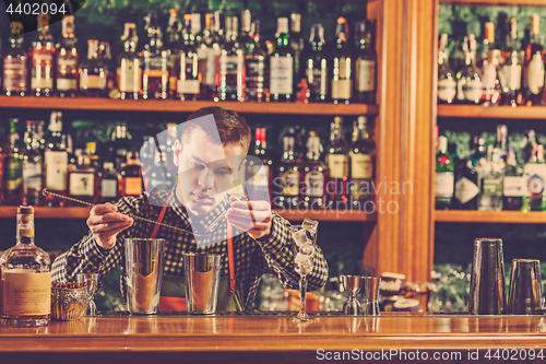 Image of Barman making an alcoholic cocktail at the bar counter on the bar background