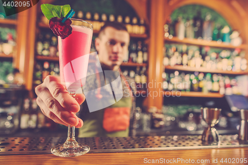 Image of Barman offering an alcoholic cocktail at the bar counter on the bar background