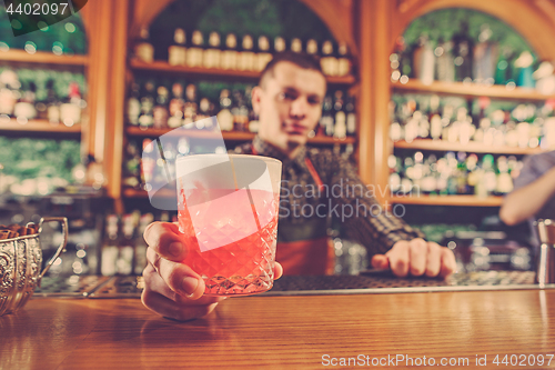 Image of Barman offering an alcoholic cocktail at the bar counter on the bar background