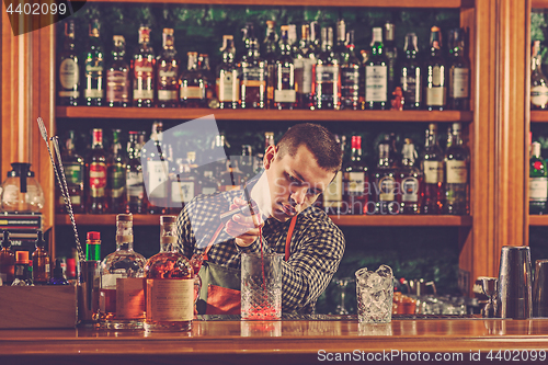 Image of Barman making an alcoholic cocktail at the bar counter on the bar background