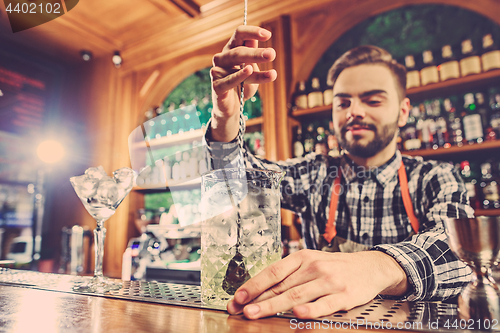 Image of Barman making an alcoholic cocktail at the bar counter on the bar background