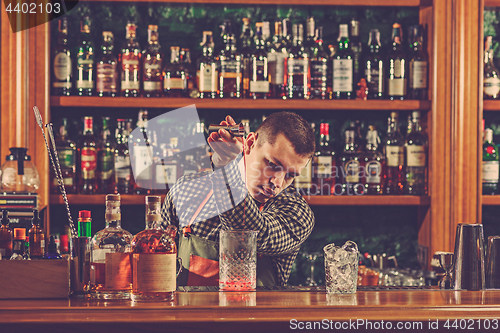 Image of Barman making an alcoholic cocktail at the bar counter on the bar background