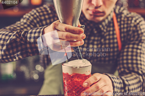 Image of Barman making an alcoholic cocktail at the bar counter on the bar background