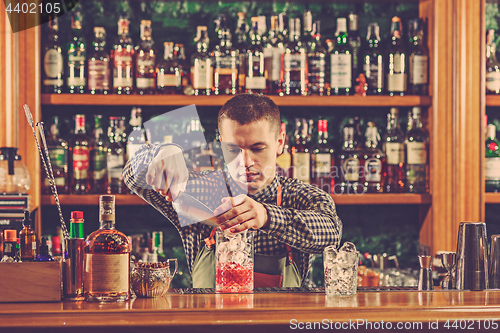 Image of Barman making an alcoholic cocktail at the bar counter on the bar background