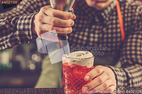 Image of Barman making an alcoholic cocktail at the bar counter on the bar background