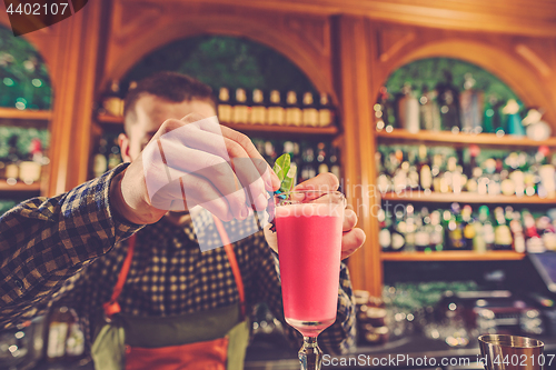 Image of Barman making an alcoholic cocktail at the bar counter on the bar background