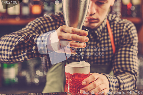 Image of Barman making an alcoholic cocktail at the bar counter on the bar background