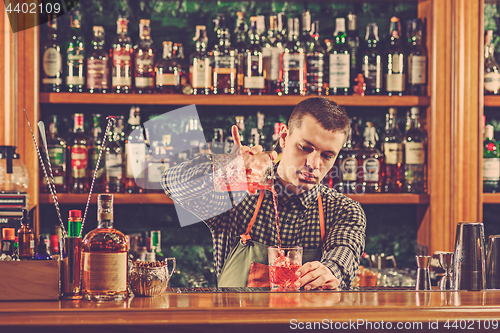 Image of Barman making an alcoholic cocktail at the bar counter on the bar background