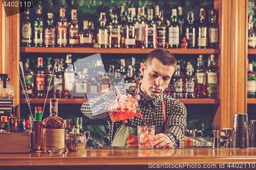 Image of Barman making an alcoholic cocktail at the bar counter on the bar background