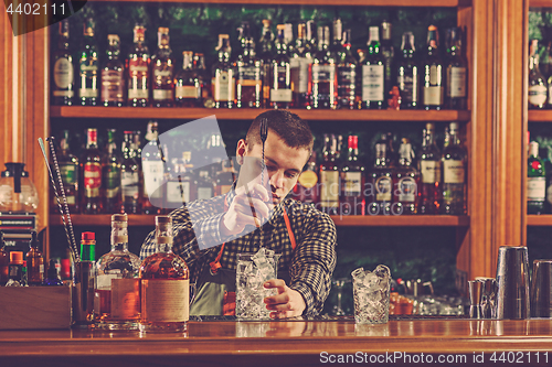 Image of Barman making an alcoholic cocktail at the bar counter on the bar background