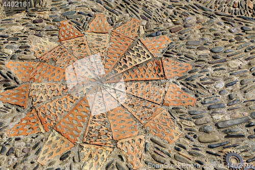 Image of Patterned floor with sea pebbles red bricks and metal gears