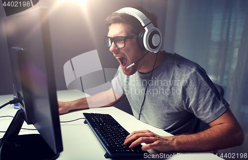 Image of man in headset playing computer video game at home