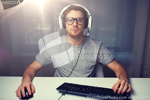 Image of man in headset playing computer video game at home