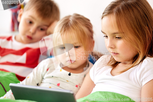 Image of little kids with tablet pc in bed at home