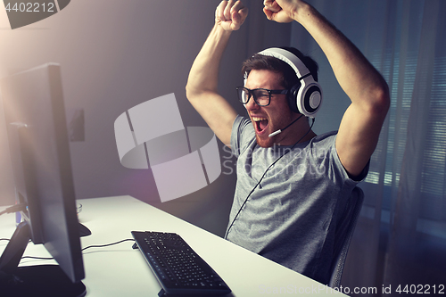 Image of man in headset playing computer video game at home