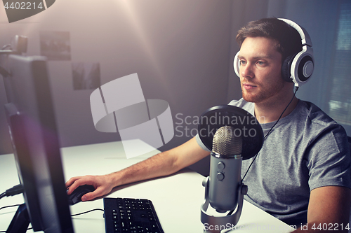 Image of man in headset playing computer video game at home