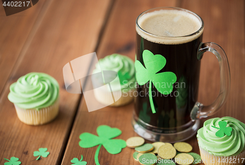 Image of shamrock on glass of beer, green cupcakes and coins