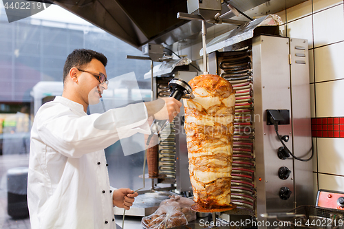 Image of chef slicing doner meat from spit at kebab shop