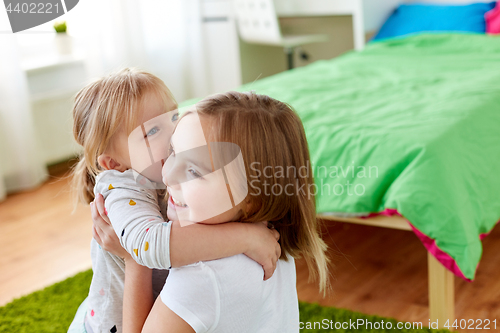 Image of happy little girls or sisters hugging at home