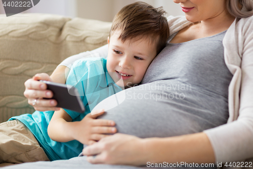 Image of pregnant mother and son with smartphone at home