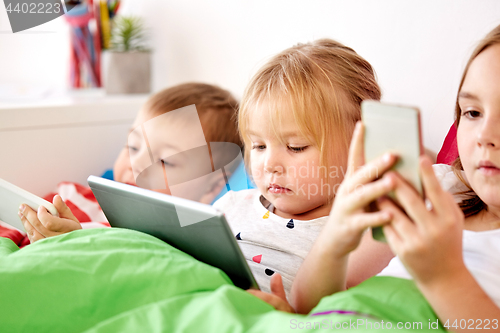 Image of little kids with tablet pc in bed at home