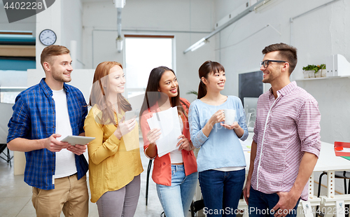 Image of happy creative team drinking coffee at office