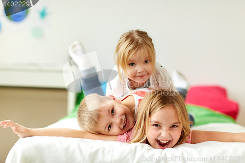 Image of happy little kids having fun in bed at home