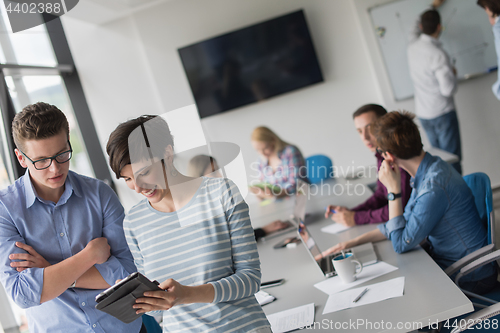 Image of Two Business People Working With Tablet in office