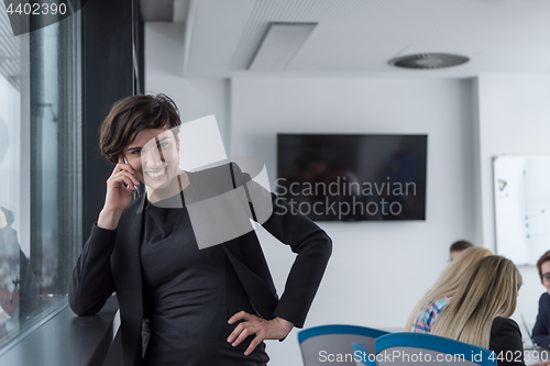 Image of Elegant Woman Using Mobile Phone by window in office building