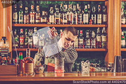 Image of Barman making an alcoholic cocktail at the bar counter on the bar background