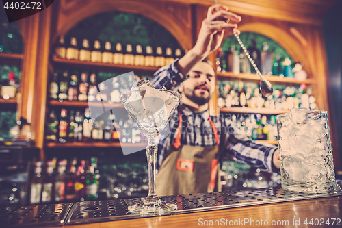 Image of Barman making an alcoholic cocktail at the bar counter on the bar background