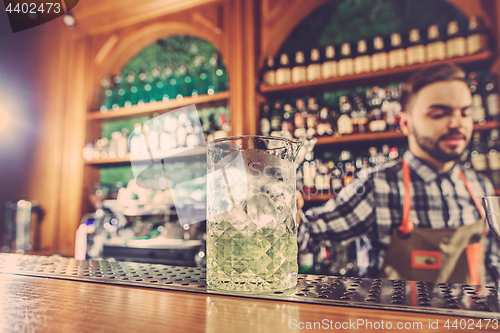 Image of Barman making an alcoholic cocktail at the bar counter on the bar background