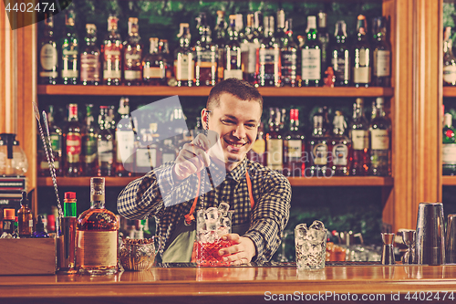 Image of Barman making an alcoholic cocktail at the bar counter on the bar background