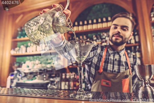 Image of Barman making an alcoholic cocktail at the bar counter on the bar background