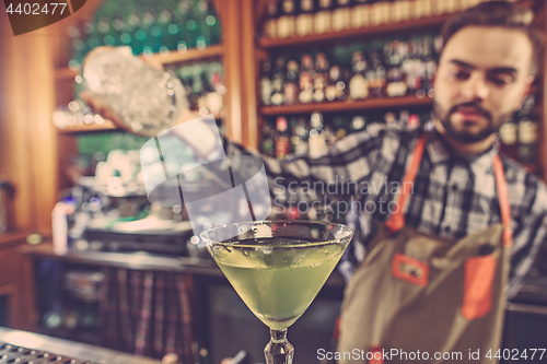 Image of Barman making an alcoholic cocktail at the bar counter on the bar background