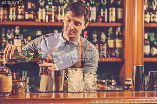 Image of Expert barman is making cocktail at night club.