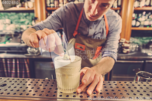 Image of Expert barman is making cocktail at night club.