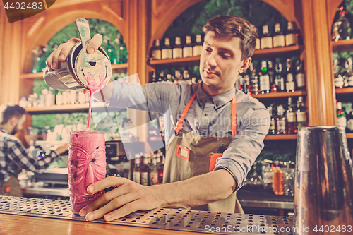 Image of Expert barman is making cocktail at night club.