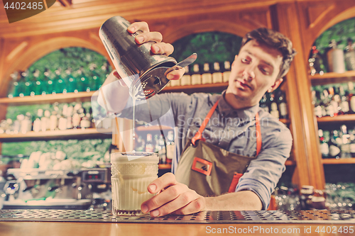 Image of Expert barman is making cocktail at night club.