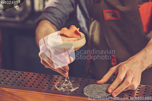Image of Barman offering an alcoholic cocktail at the bar counter on the bar background