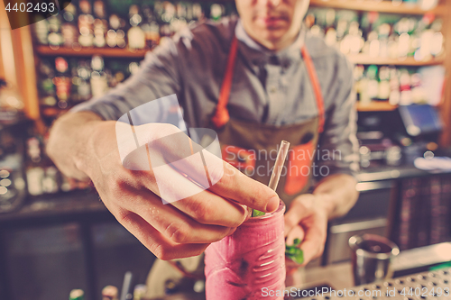 Image of Expert barman is making cocktail at night club.