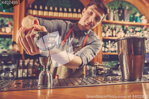 Image of Expert barman is making cocktail at night club.