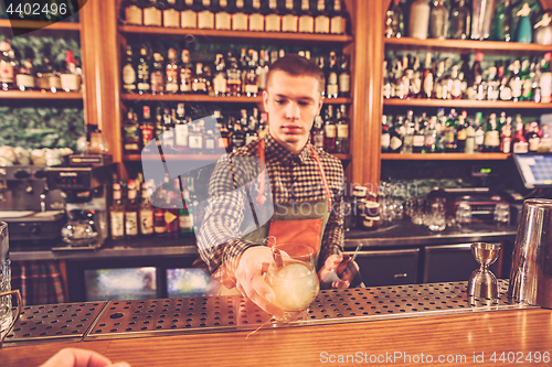 Image of Barman making an alcoholic cocktail at the bar counter on the bar background