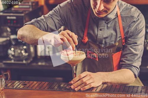 Image of Expert barman is making cocktail at night club.