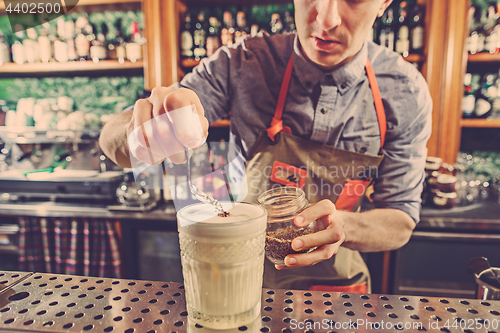 Image of Expert barman is making cocktail at night club.