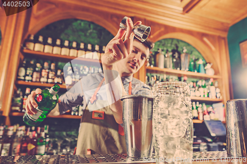 Image of Expert barman is making cocktail at night club.