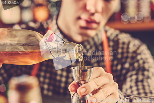 Image of Barman making an alcoholic cocktail at the bar counter on the bar background